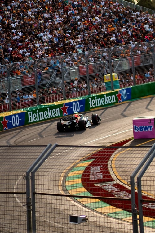 Two F1 cars racing wheel-to-wheel before packed grandstands