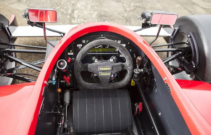 Lola F1R cockpit showing Momo steering wheel, wing mirrors, and gear lever